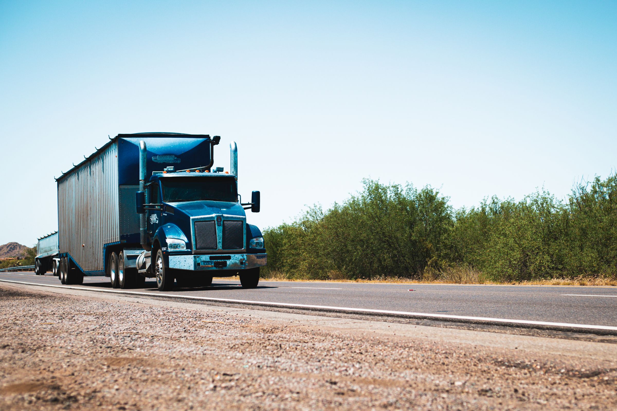 Blue American semi truck on a bright open highway